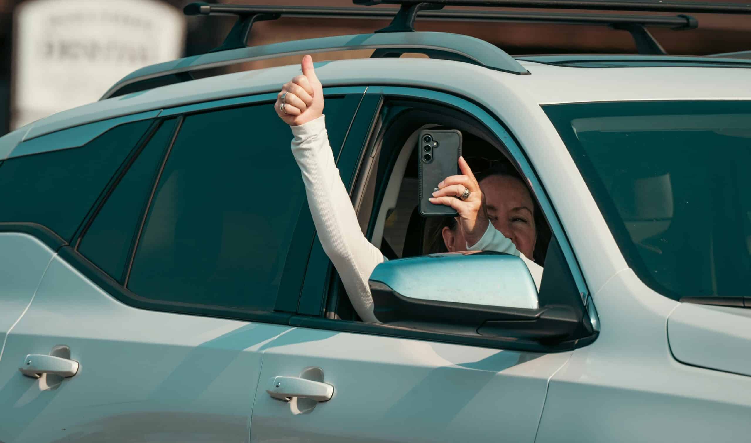 Happy buddii customer giving a thumbs up from their new car