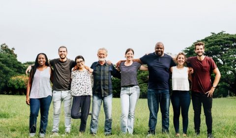 A group of people standing arm in arm in a park